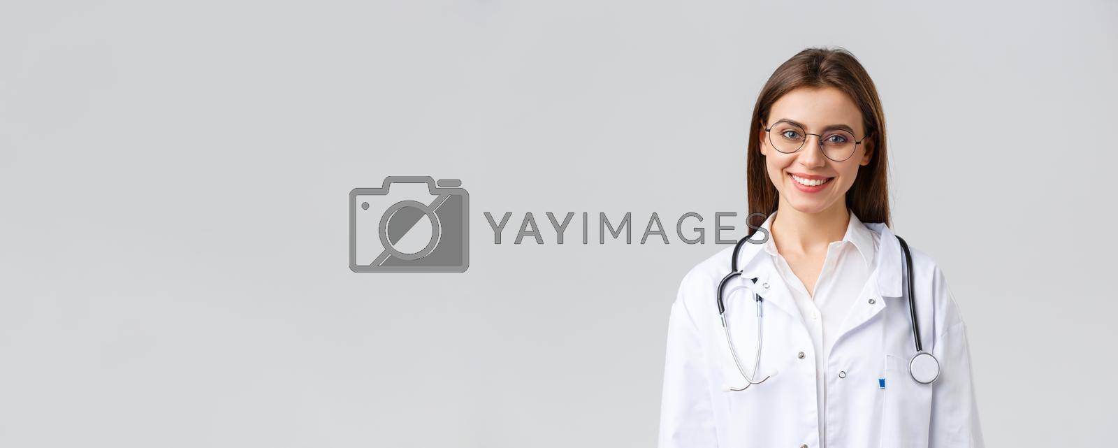 Healthcare workers, medicine, insurance and covid-19 pandemic concept. Smiling attractive female doctor, physician in white scrubs with stethoscope and glasses look upbeat at camera.