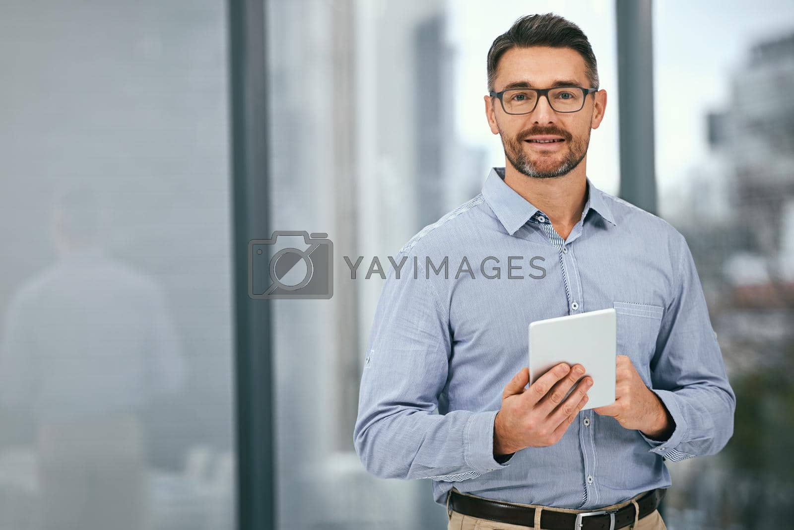 Royalty free image of Its how I choose to do business. Portrait of a mature businessman using a digital tablet in an office. by YuriArcurs