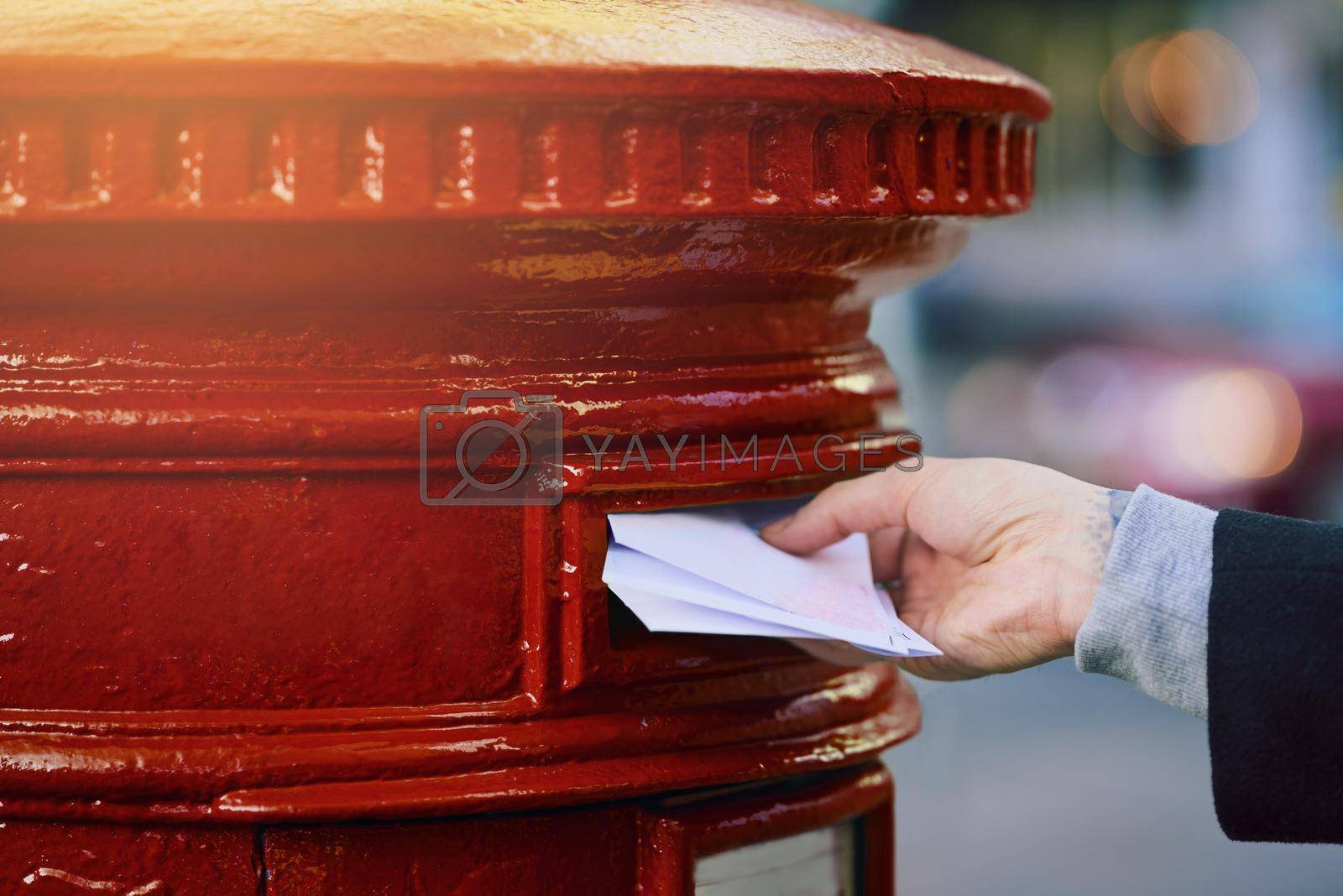 Cropped shot of a man posting mail into a postbox in the city.