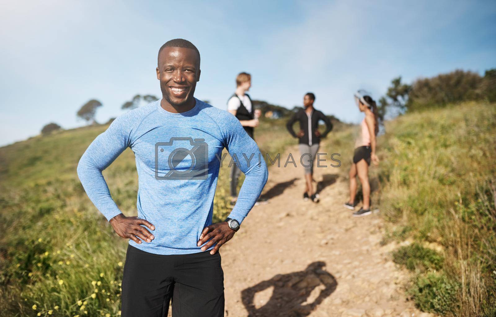 Portrait of a young man exercising outside with people in the background.