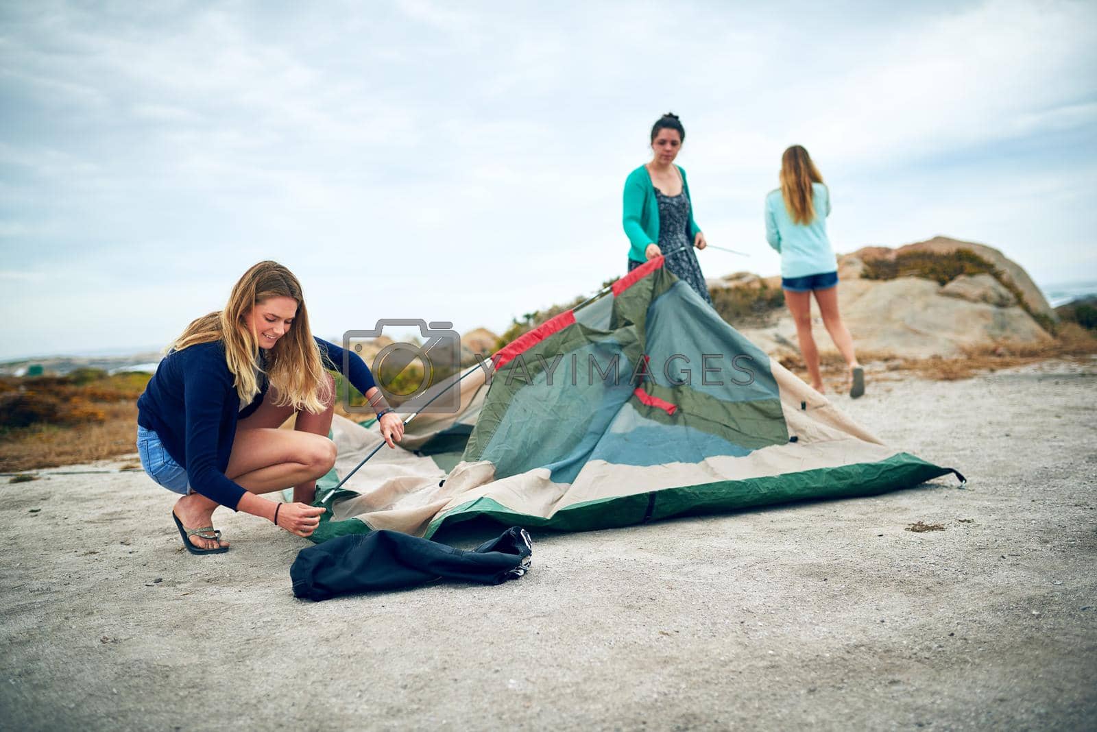 Shot of a group of female friends setting up a tent outdoors.