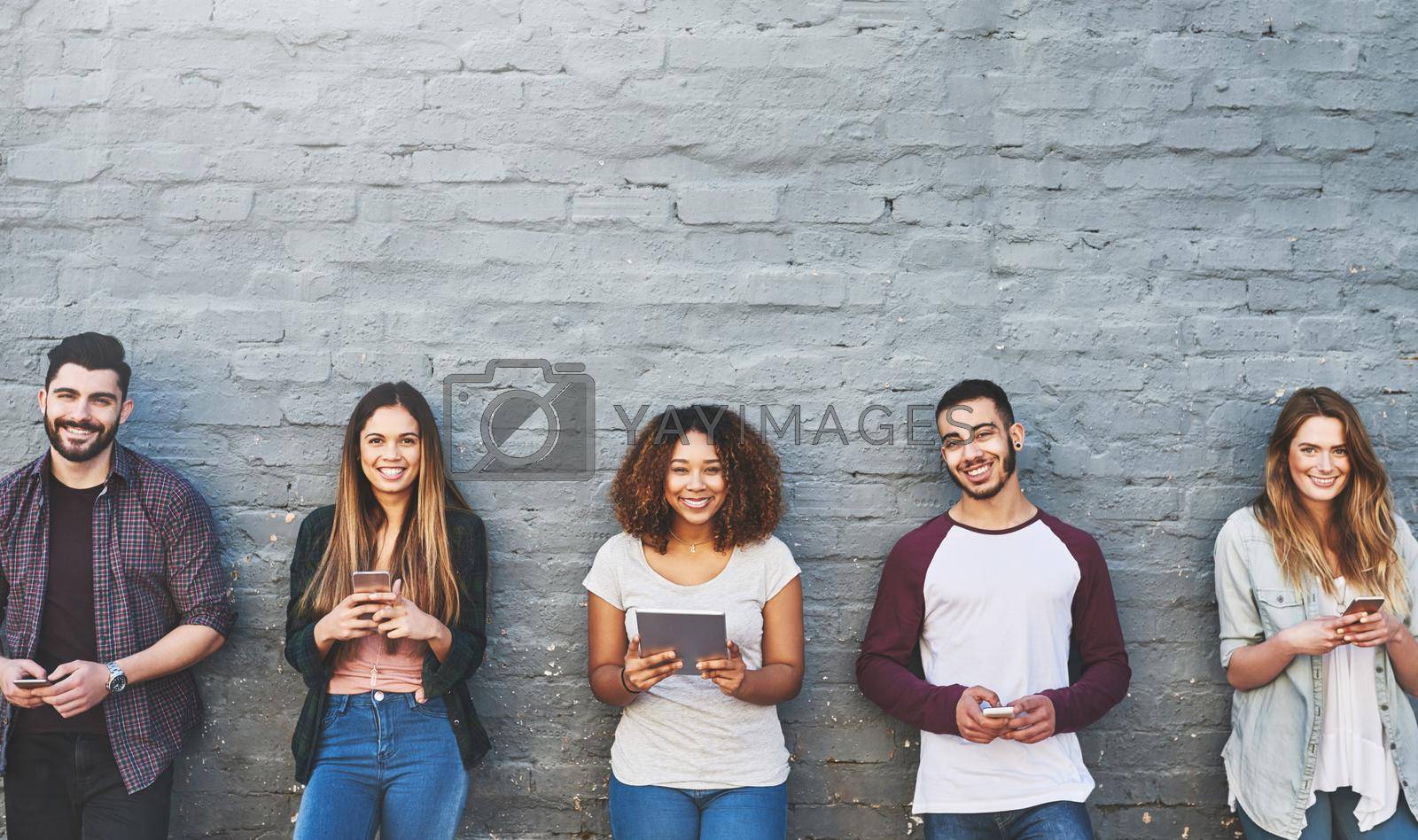 Portrait of a group of young people using their wireless devices together outdoors.