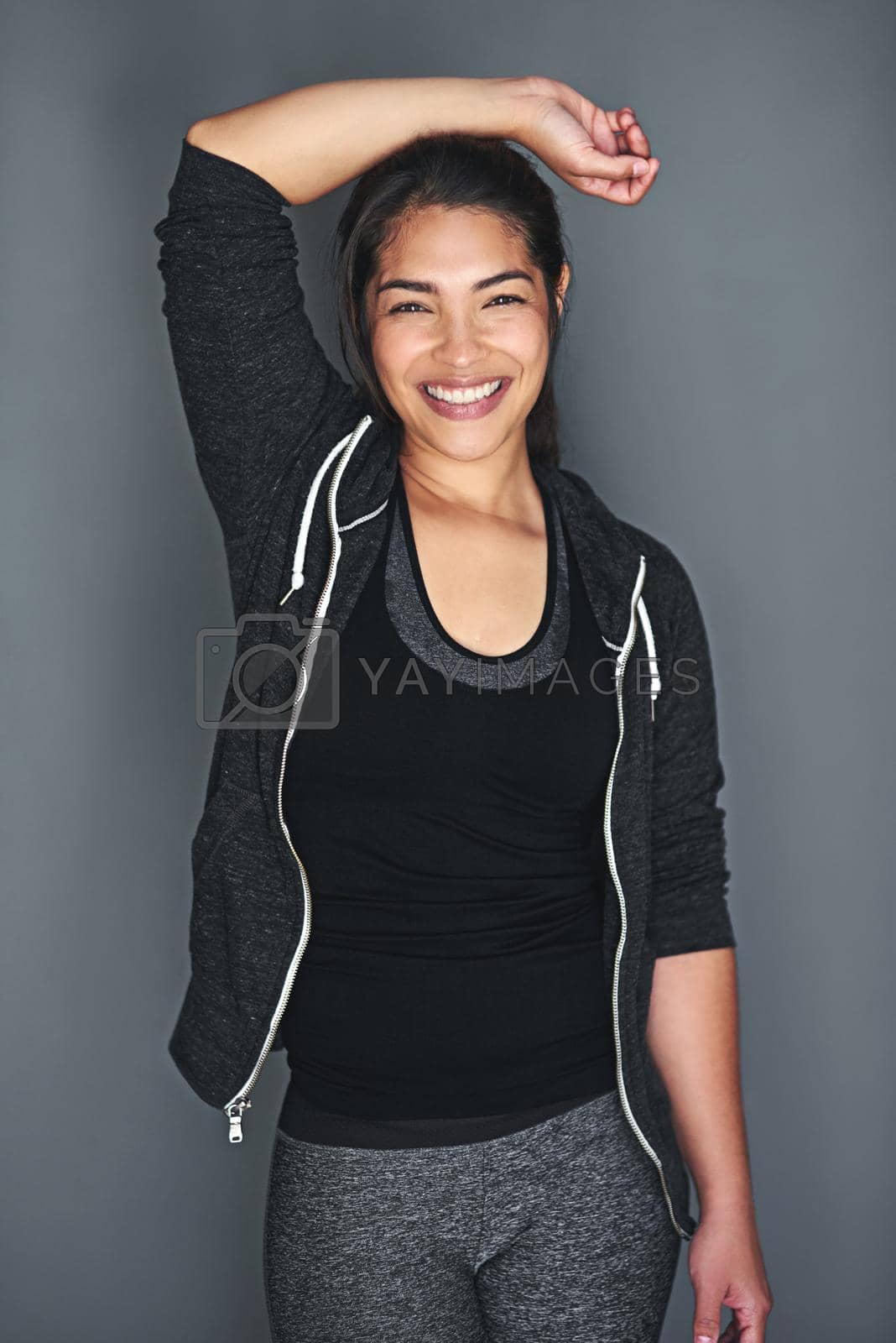Royalty free image of She thrives on exercise. Portrait of a fit young woman in sports clothing posing against a gray background. by YuriArcurs