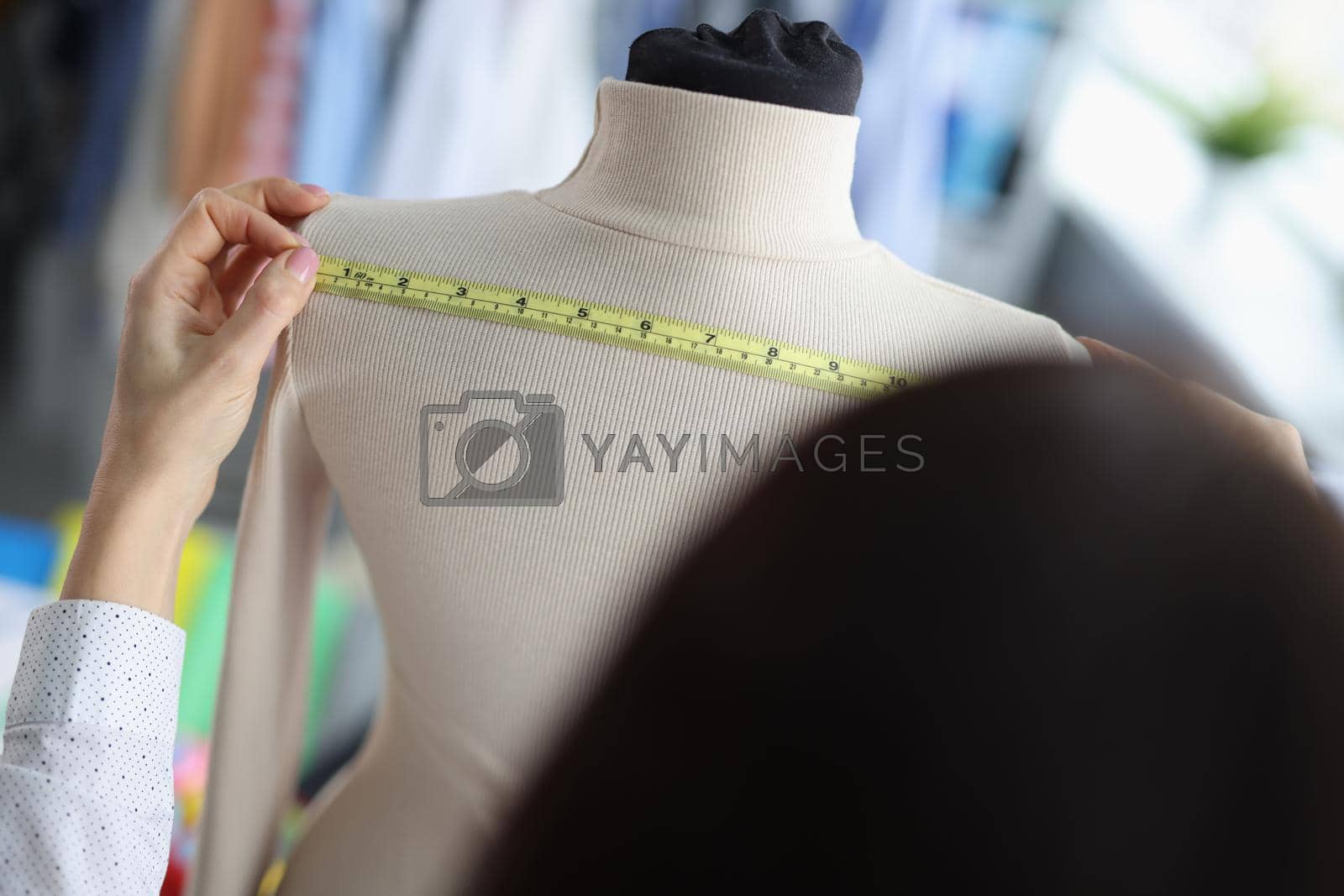 Fashion designer stylist takes measurements of clothes on mannequin. Tailoring in atelier concept