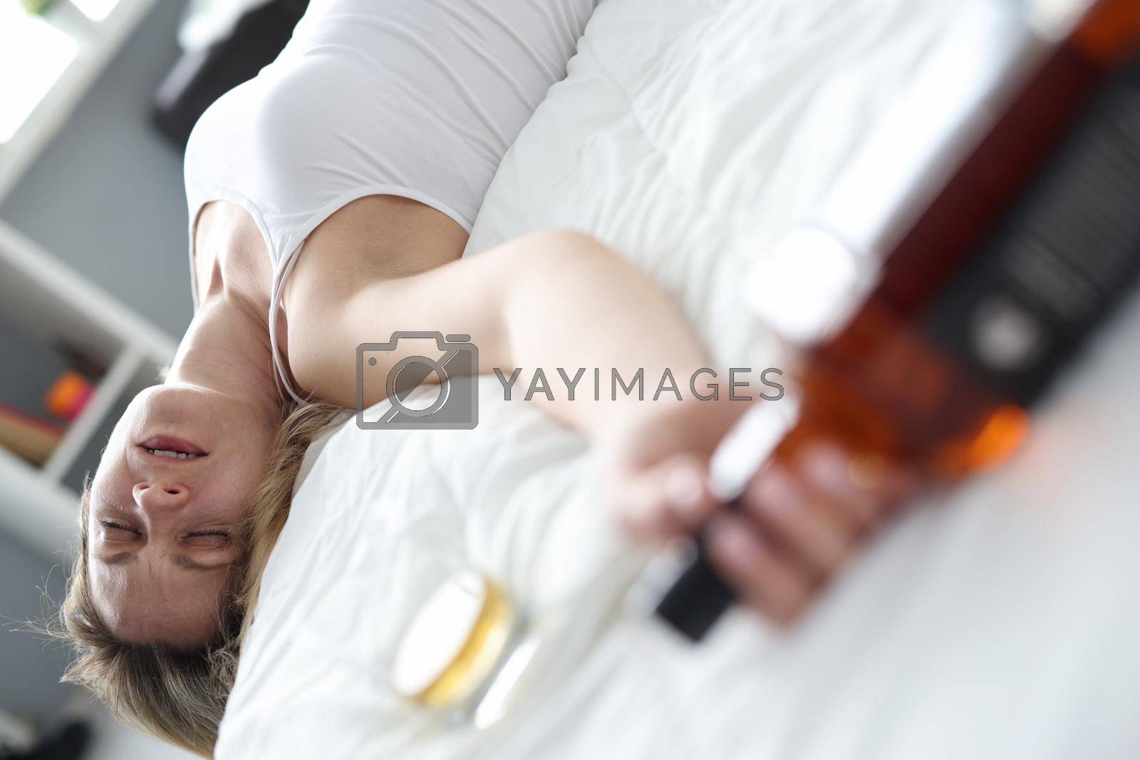 Royalty free image of Drunk woman sleeping with bottle of alcohol in bed closeup by kuprevich