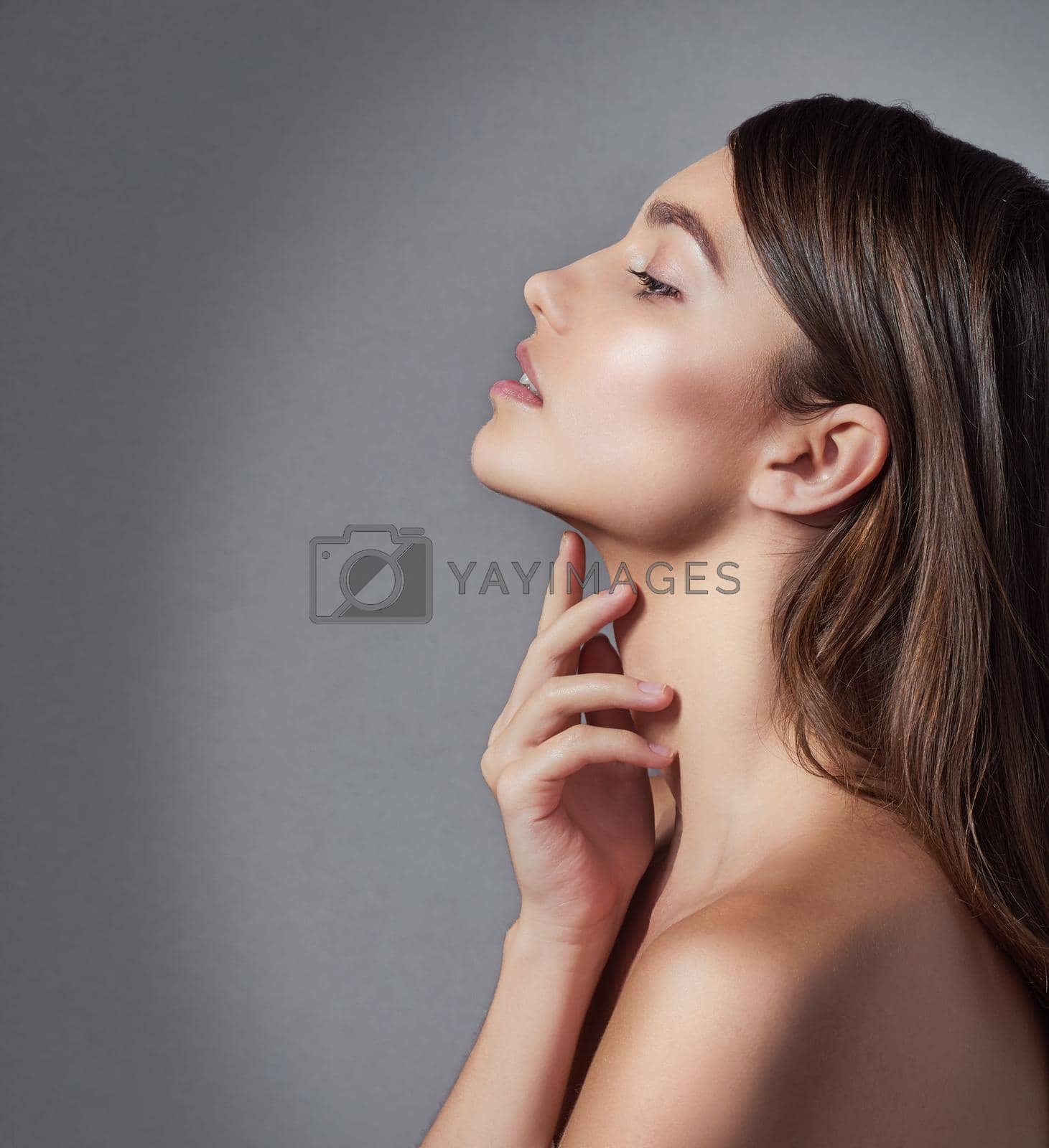 Studio shot of a beautiful young woman posing against a gray background.
