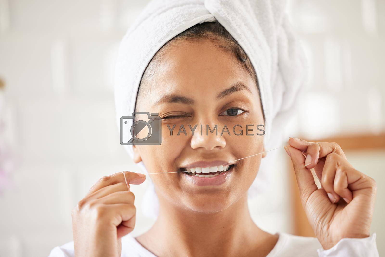 Shot of an attractive young woman flossing her teeth in the bathroom.