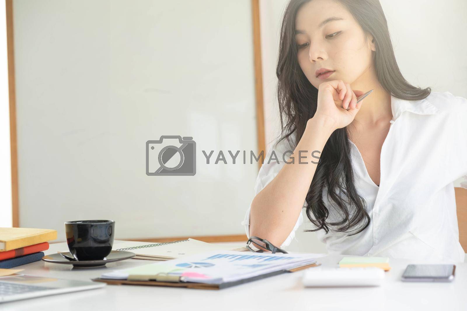 Royalty free image of Young asian entrepreneur cogitating thinking making important decision at workplace. Concentrated serious office worker millennial woman analysing results by nateemee