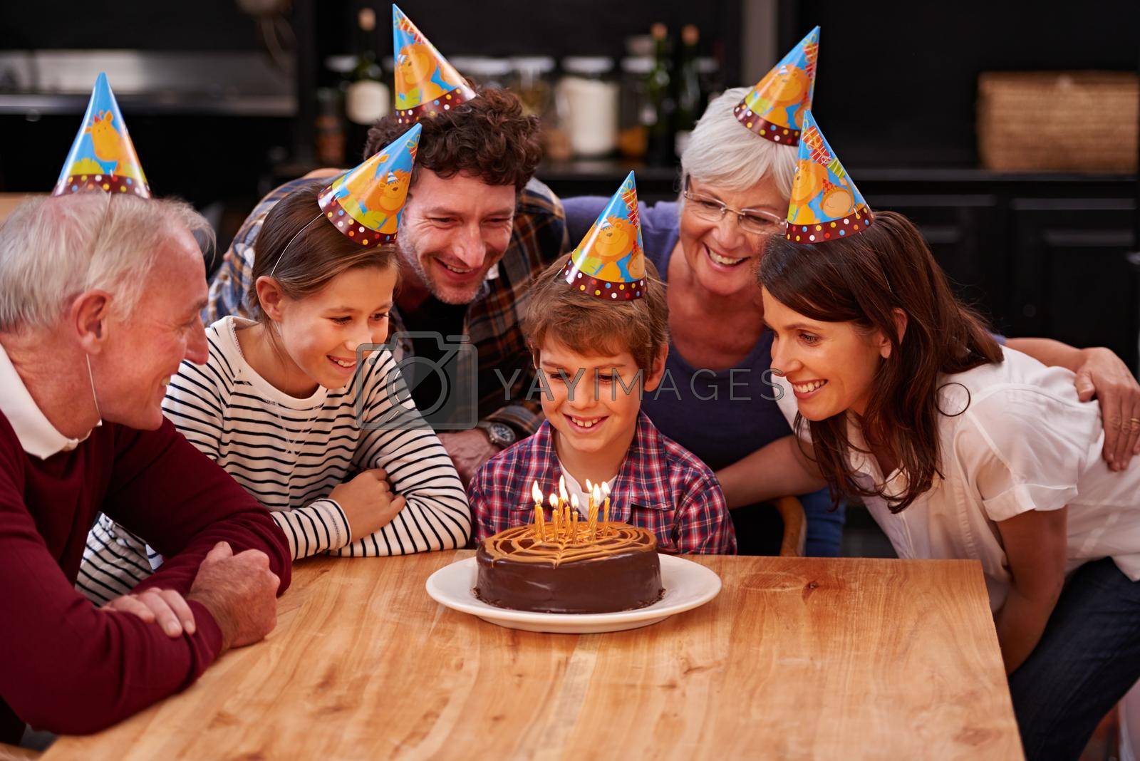 Royalty free image of Make a wish before you blow them out. Shot of a happy young boy celebrating his birthday with his family. by YuriArcurs