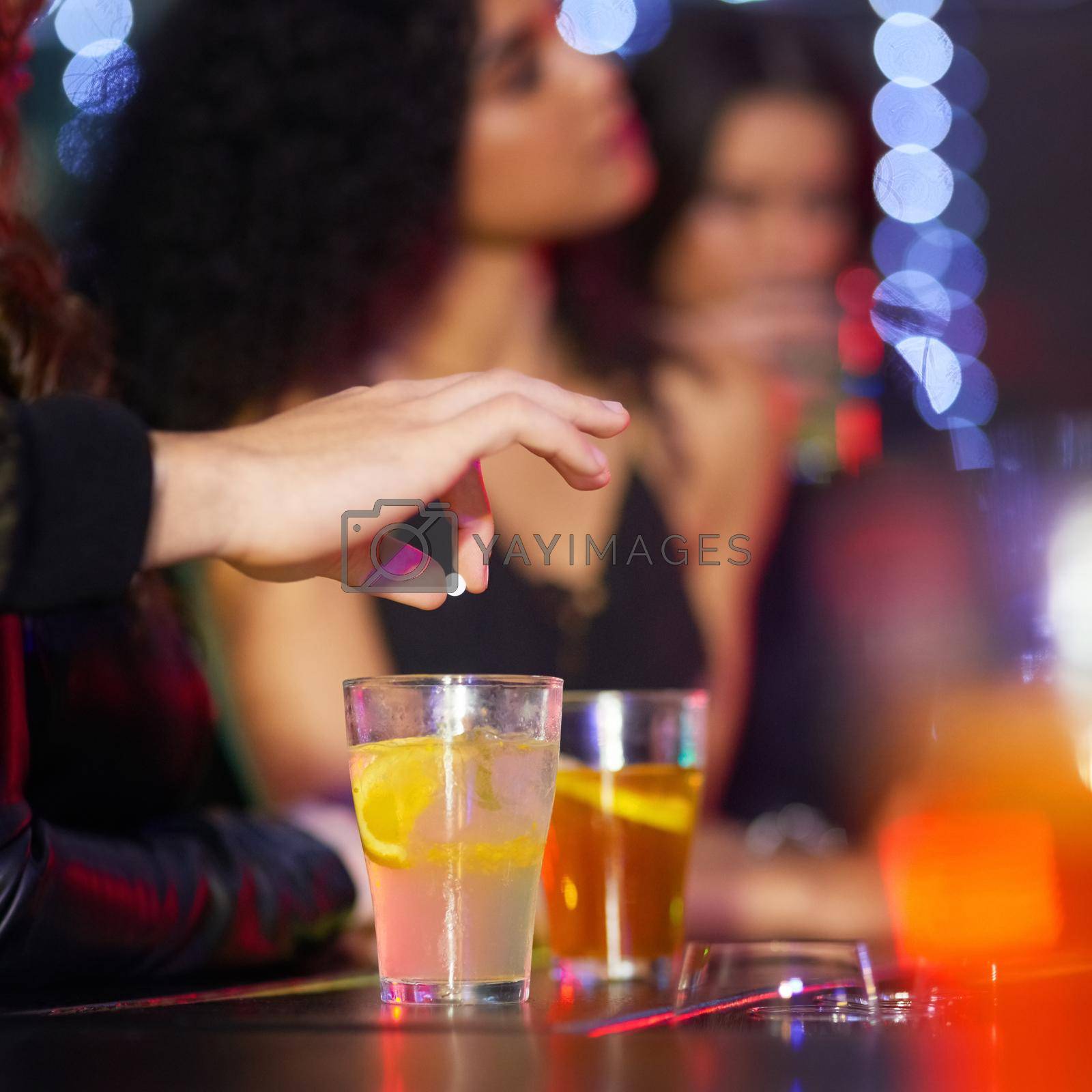 Closeup shot of a man drugging a womans drink in a nightclub.