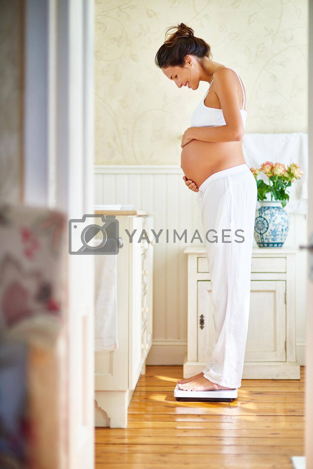 Shot of a pregnant woman standing on a scale.