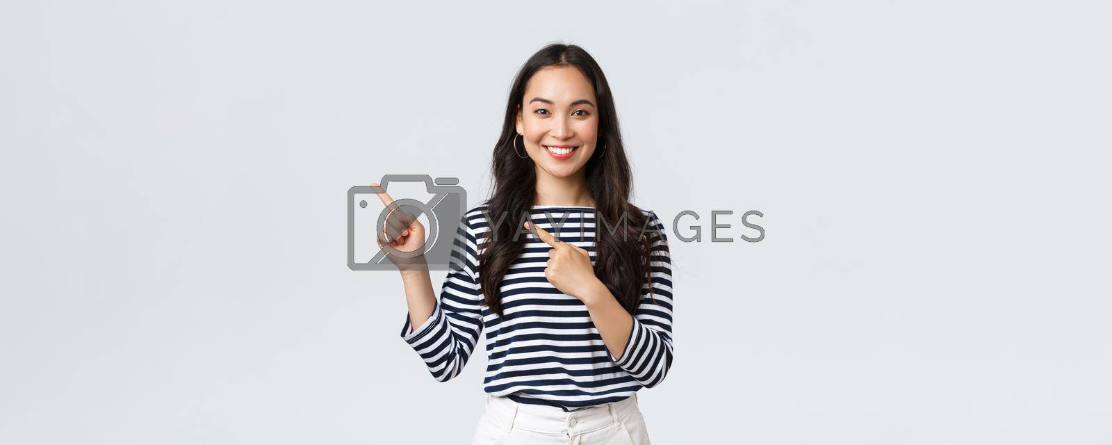 Lifestyle, people emotions and casual concept. Good-looking young korean female advertise product, smiling camera excited and pointing fingers upper left corner at promo banner.