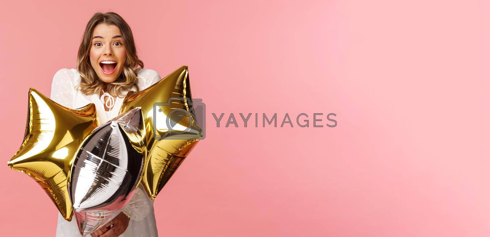Holidays, celebration and women concept. Happy charming and surprised girl being congratulated with birthday, holding star-shaped balloons and smiling joyfully camera, pink background.