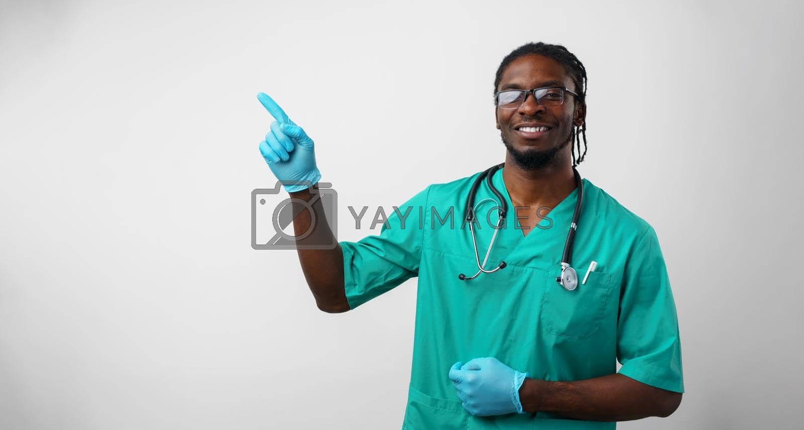 Royalty free image of Afro american doctor pointing with hand and finger to the side by Fabrikasimf