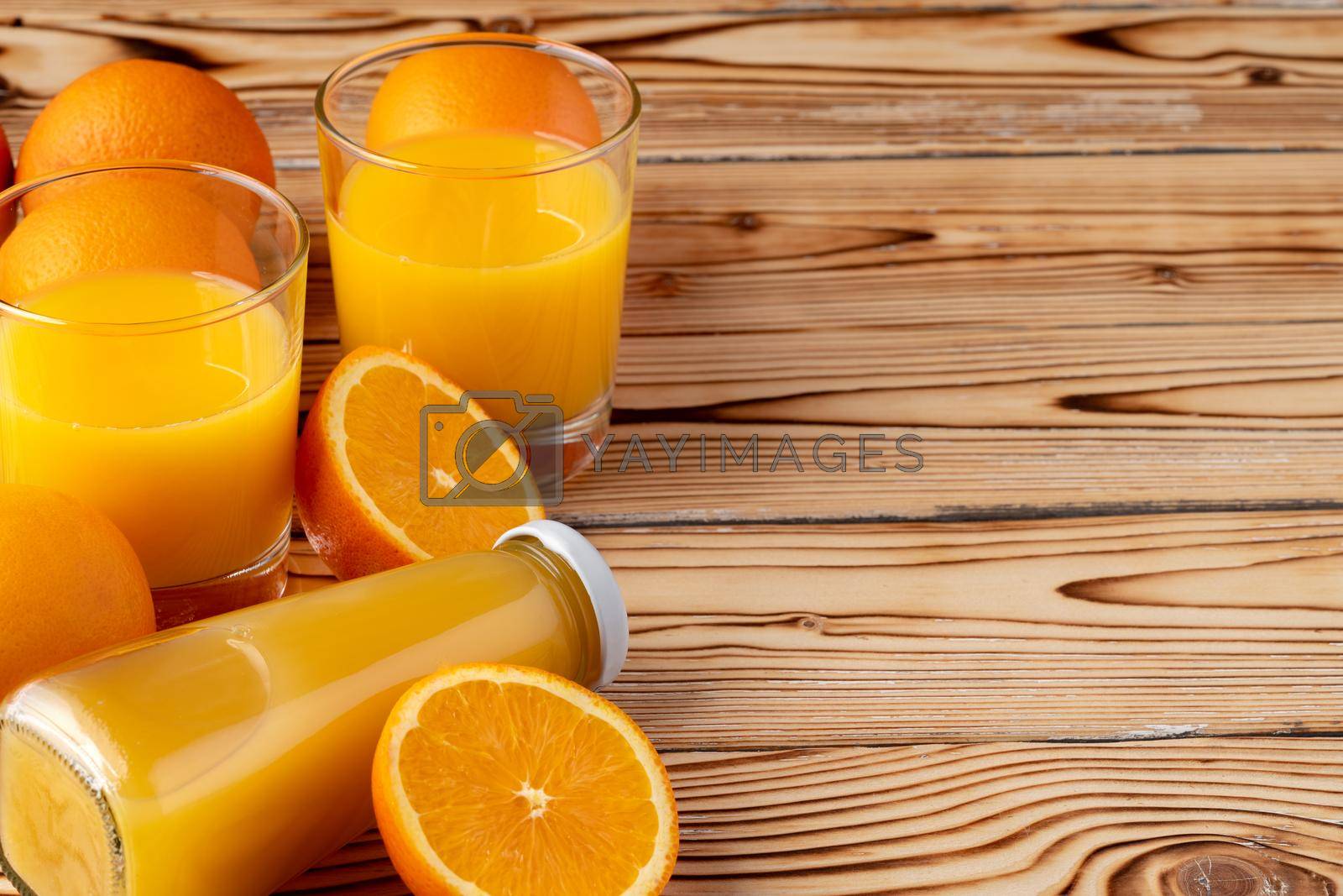 Royalty free image of Orange fruit and orange juice on wooden background by Fabrikasimf