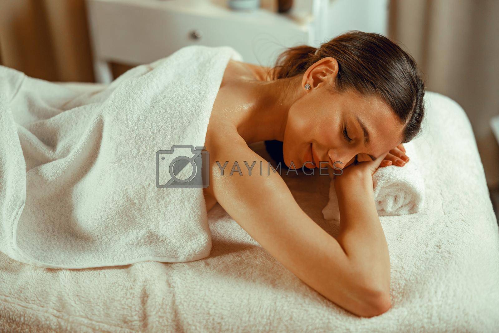 Woman relaxing with eyes closed, enjoying professional massage at spa center. Resort, therapy