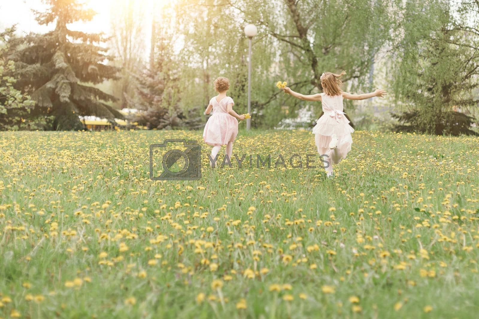 Royalty free image of two little sisters running across the lawn on a spring day . by SmartPhotoLab