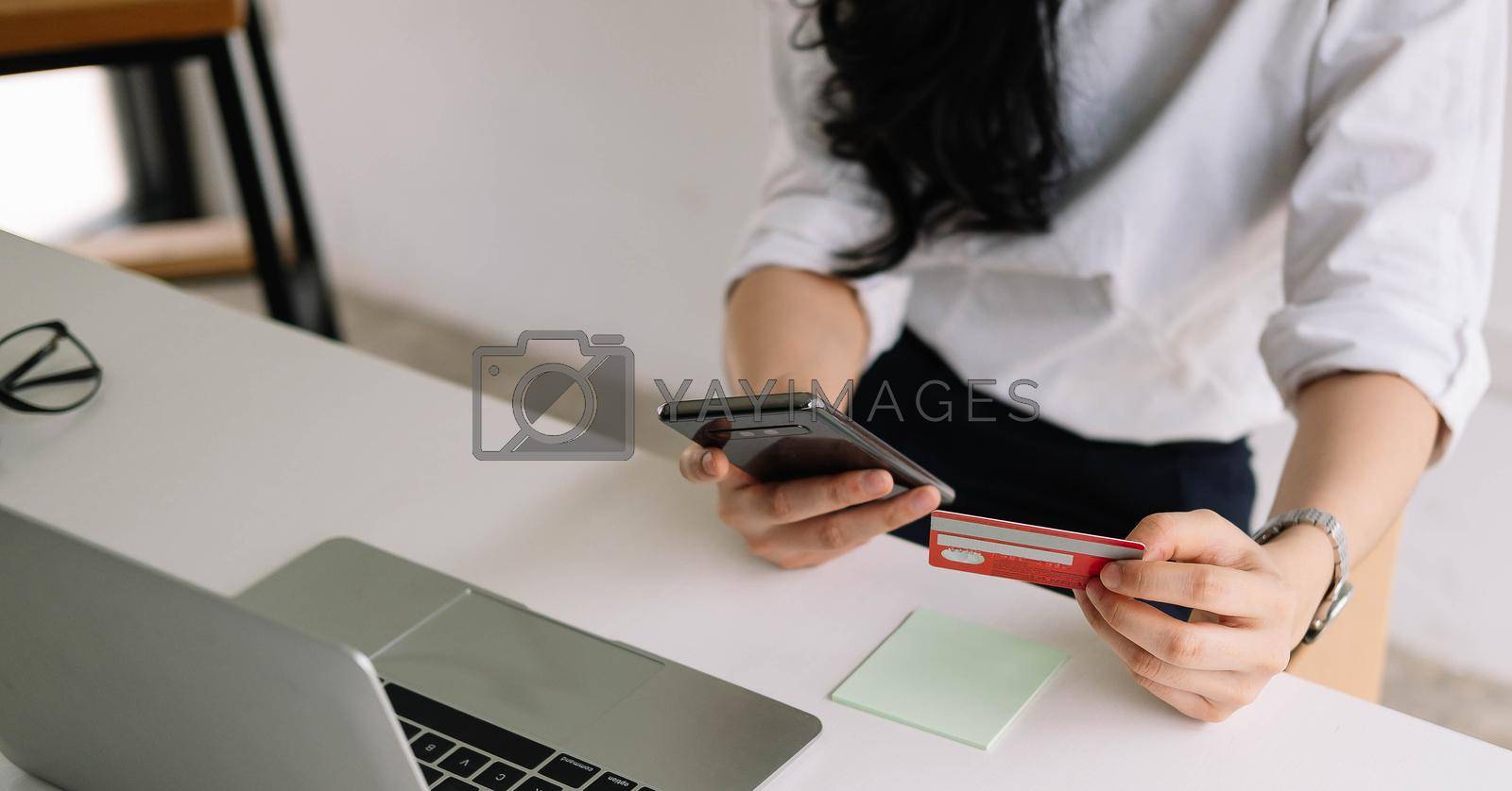 Royalty free image of Close up woman using credit card for purchasing and shopping online on mobile phone by nateemee