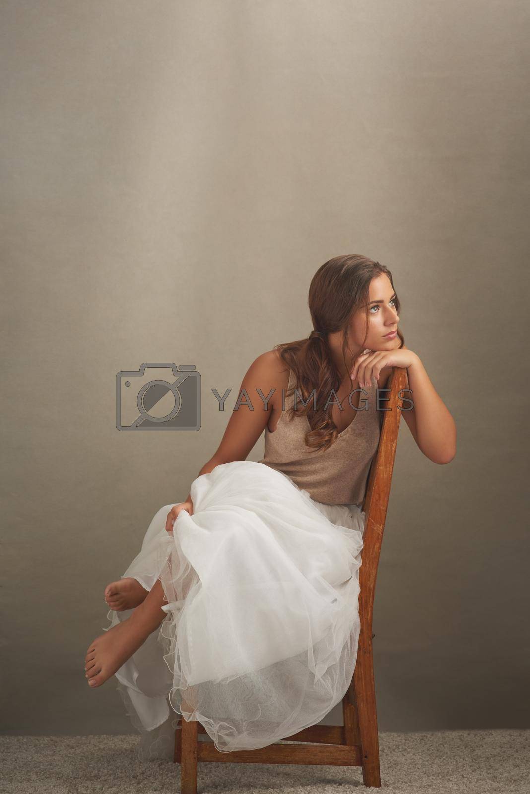 Studio shot of an attractive young woman looking thoughtful while sitting on a chair.
