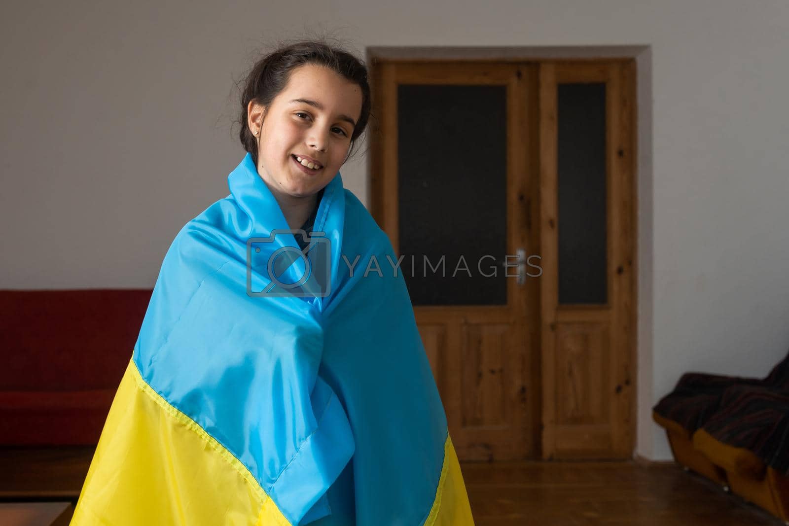 Royalty free image of little girl covered with Ukraine flag. Concept of standing with Ukrainian nation in war with Russia. by Andelov13