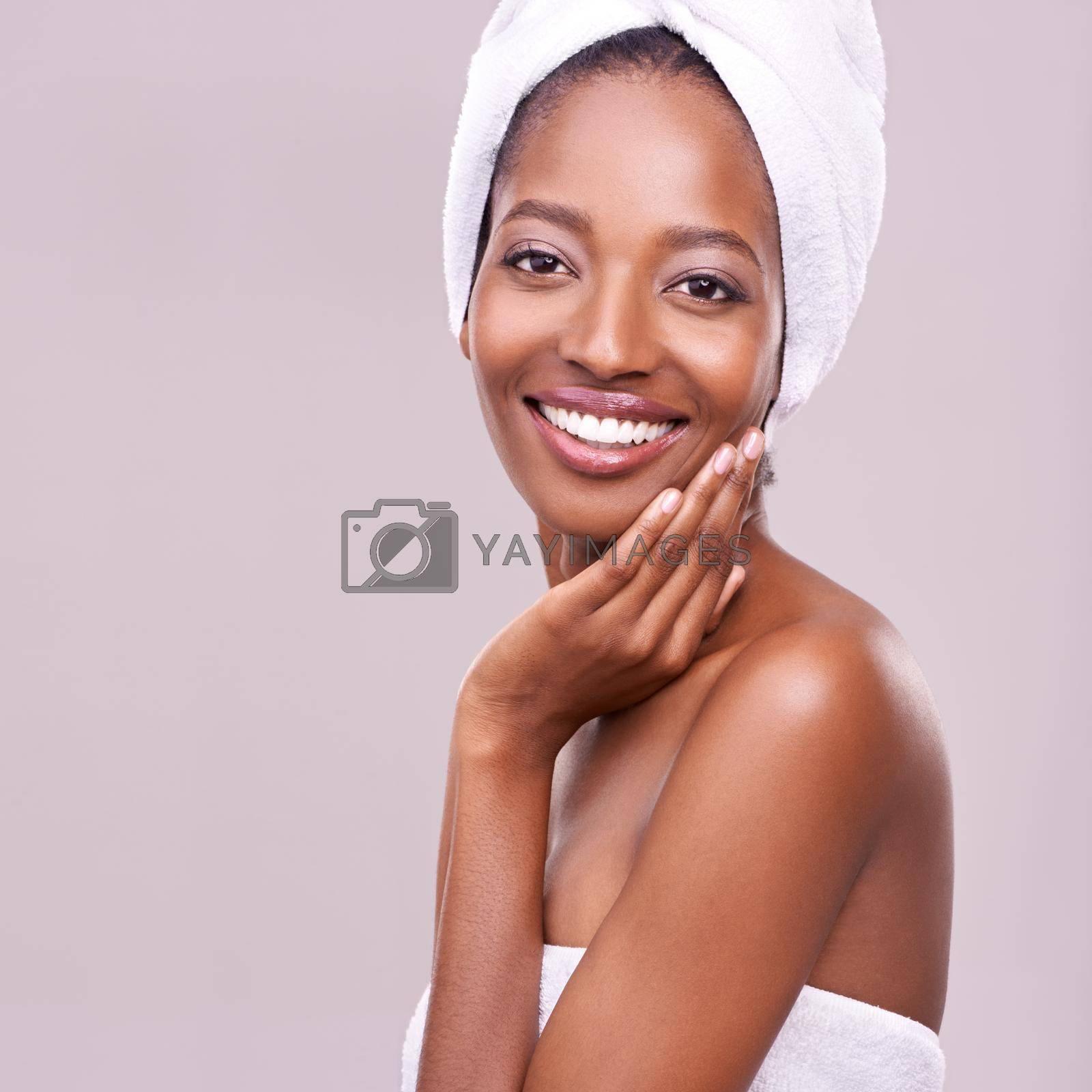 An isolated studio portrait of a beautiful young woman wearing a towel on her head.