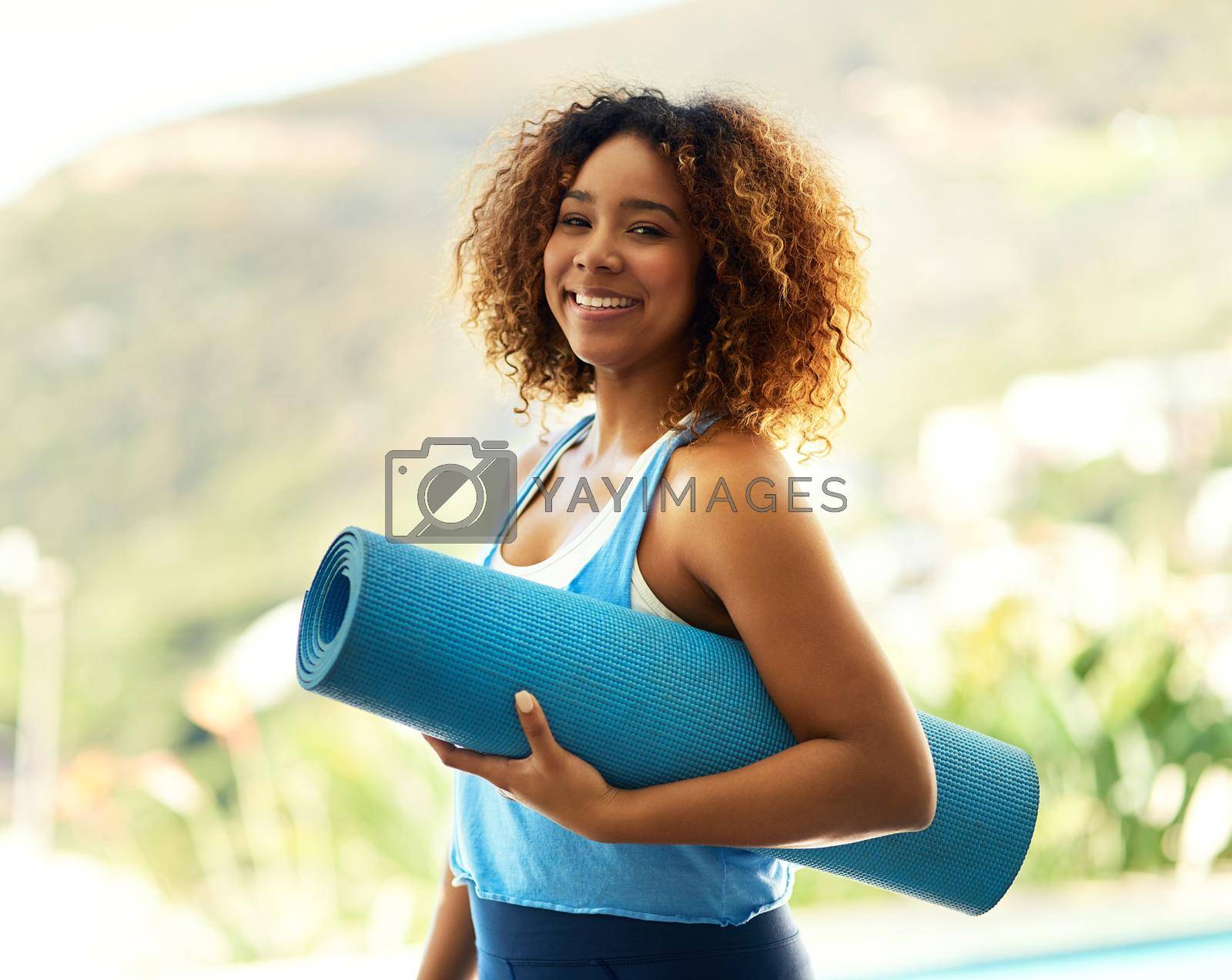 Portrait of an attractive young woman standing outside with her yoga mat.