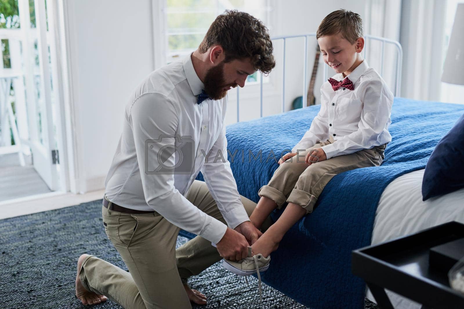 Cropped shot of a young handsome father helping his adorable son put on his shoes at home.