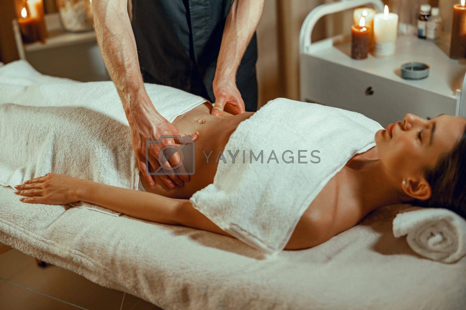 Relaxed female client getting stomach massage in spa salon. Therapy, alternative medicine