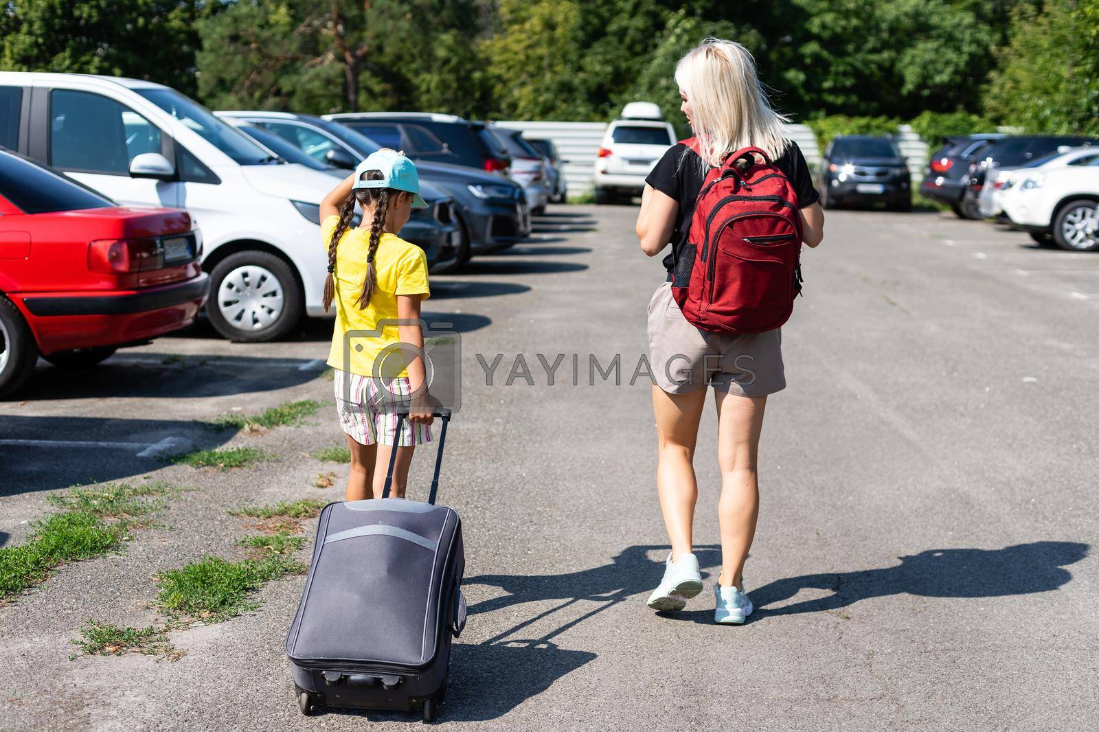 mother and daughter with suitcase in the parking lot.