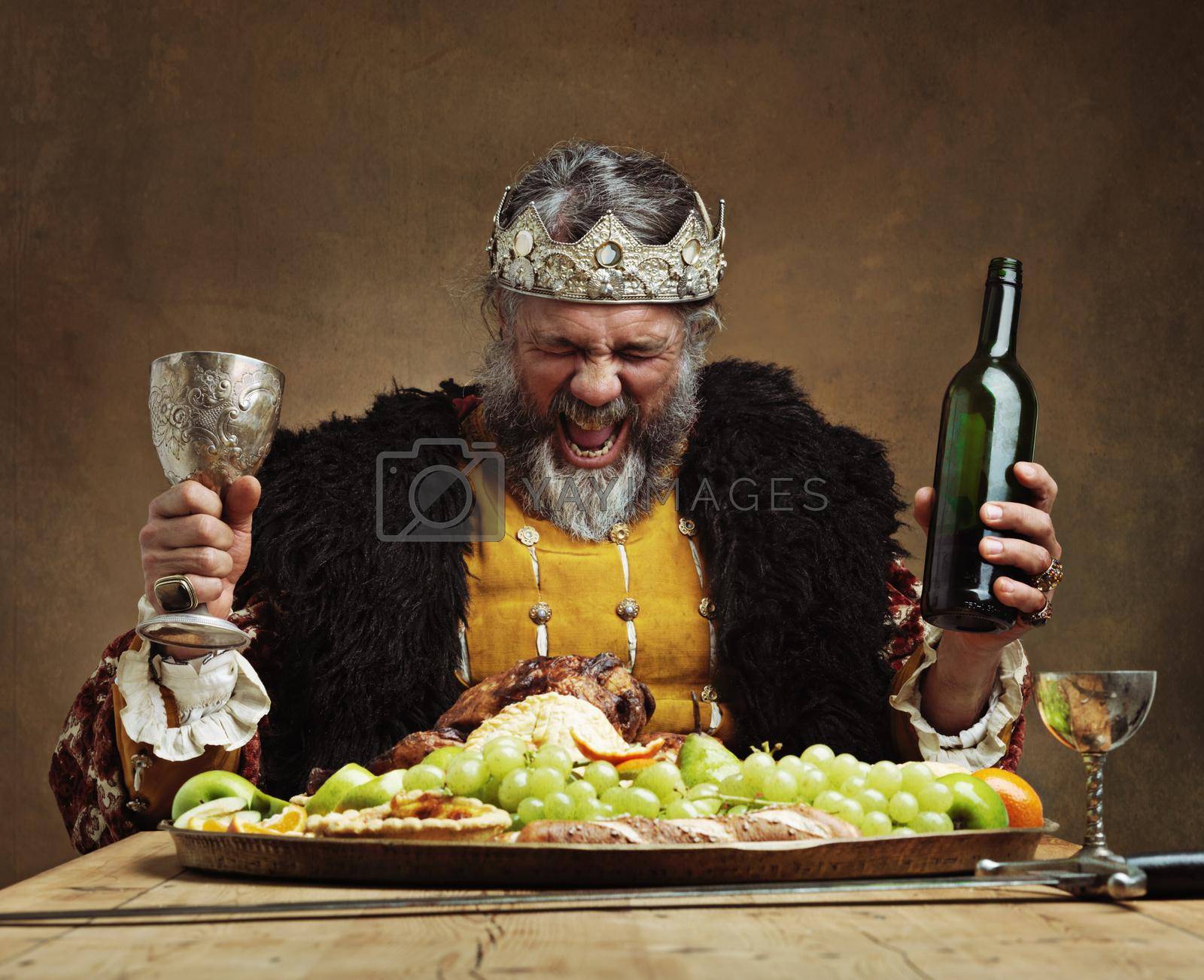 Royalty free image of Im the life of the party. A mature king feasting alone in a banquet hall. by YuriArcurs