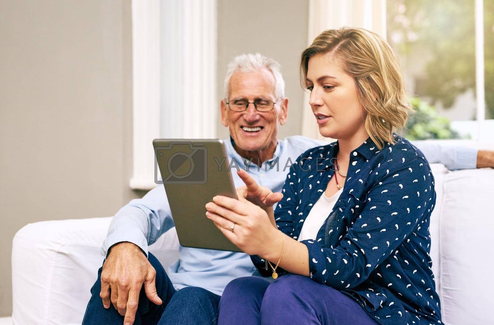 Shot of a senior father and his adult daughter using a tablet together at home.