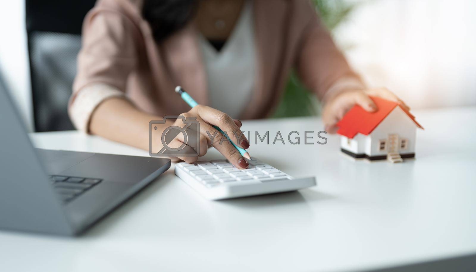 Royalty free image of Hand of Business woman calculating interest, taxes and profits to invest in real estate and home buying by nateemee