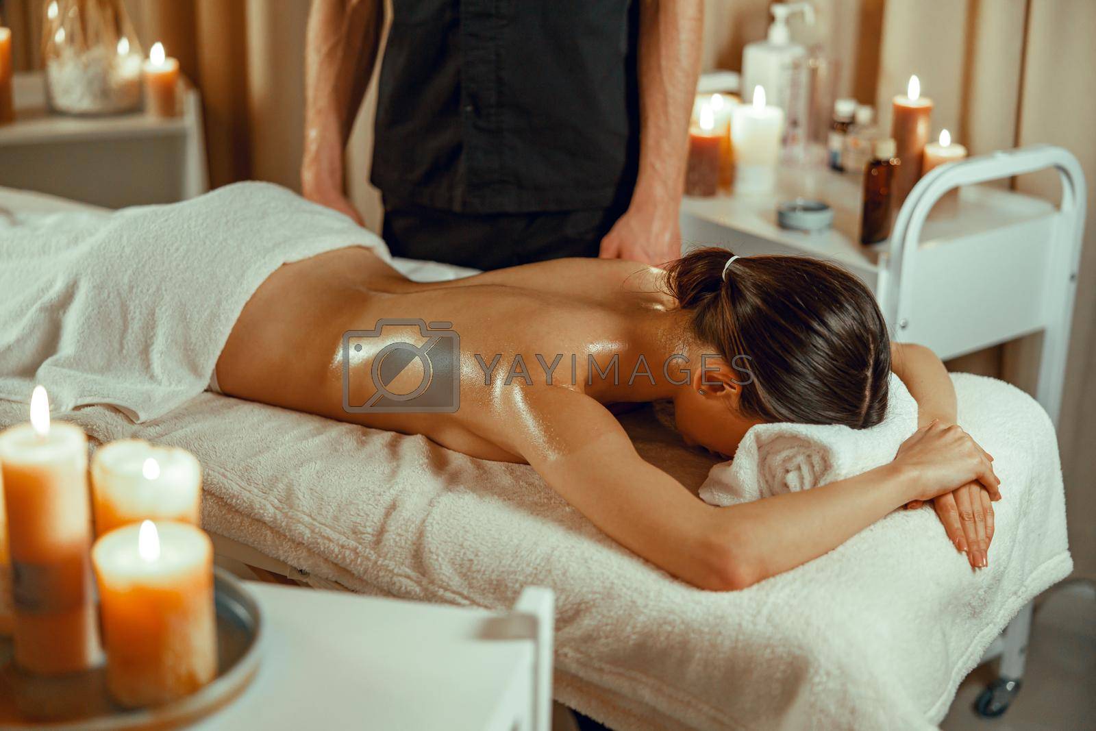 Half naked relaxed woman ready for back massage at beauty spa resort. Treatment