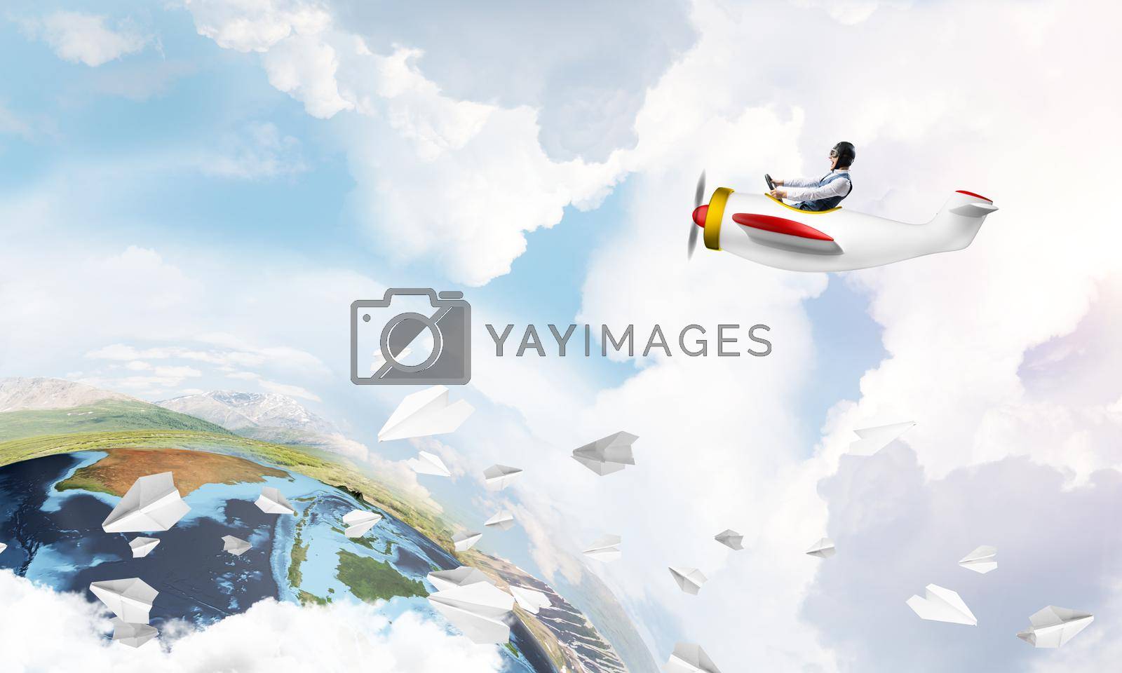 Pilot in leather helmet driving propeller plane on background of blue cloudy sky. Traveling around the world by airplane. Funny man flying in small airplane. Earth horizon with mountains and ocean