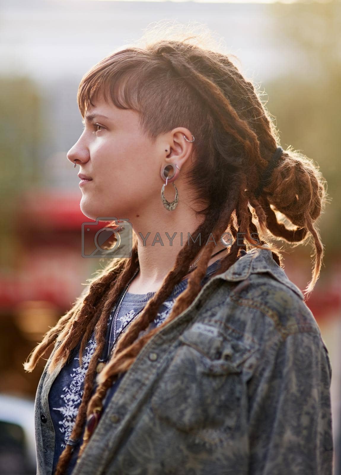 Royalty free image of On top of the latest trends. Shot of a young woman with dreadlocks and piercings posing outdoors. by YuriArcurs