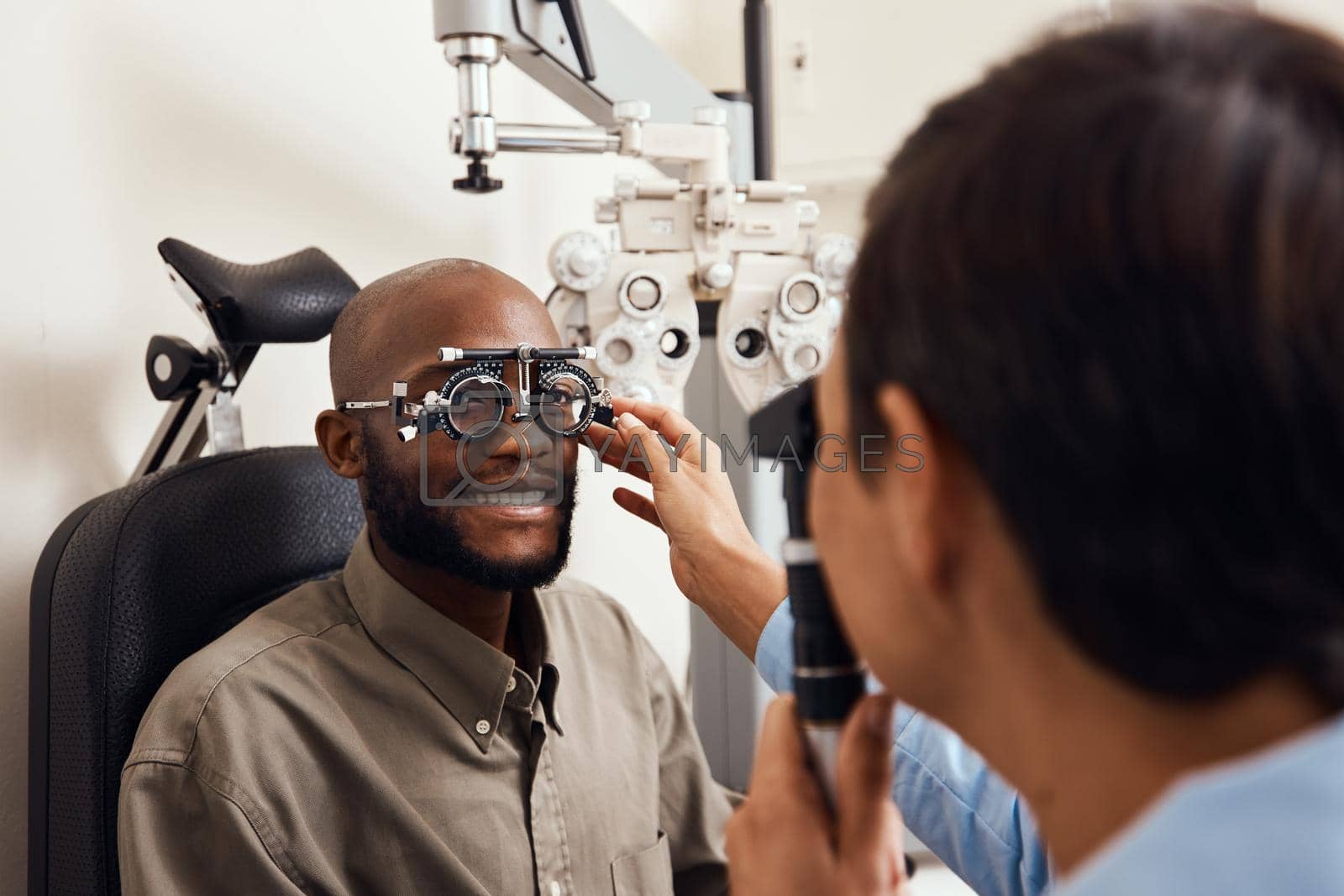 Royalty free image of It was clarity at first sight. Shot of an young man getting new glasses fitted by an optometrist. by YuriArcurs