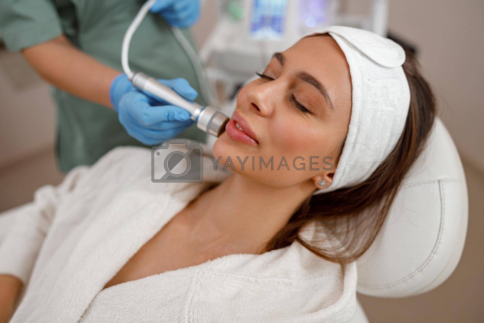 Royalty free image of Female client getting aesthetic facial skin treatment in beauty salon by Yaroslav_astakhov