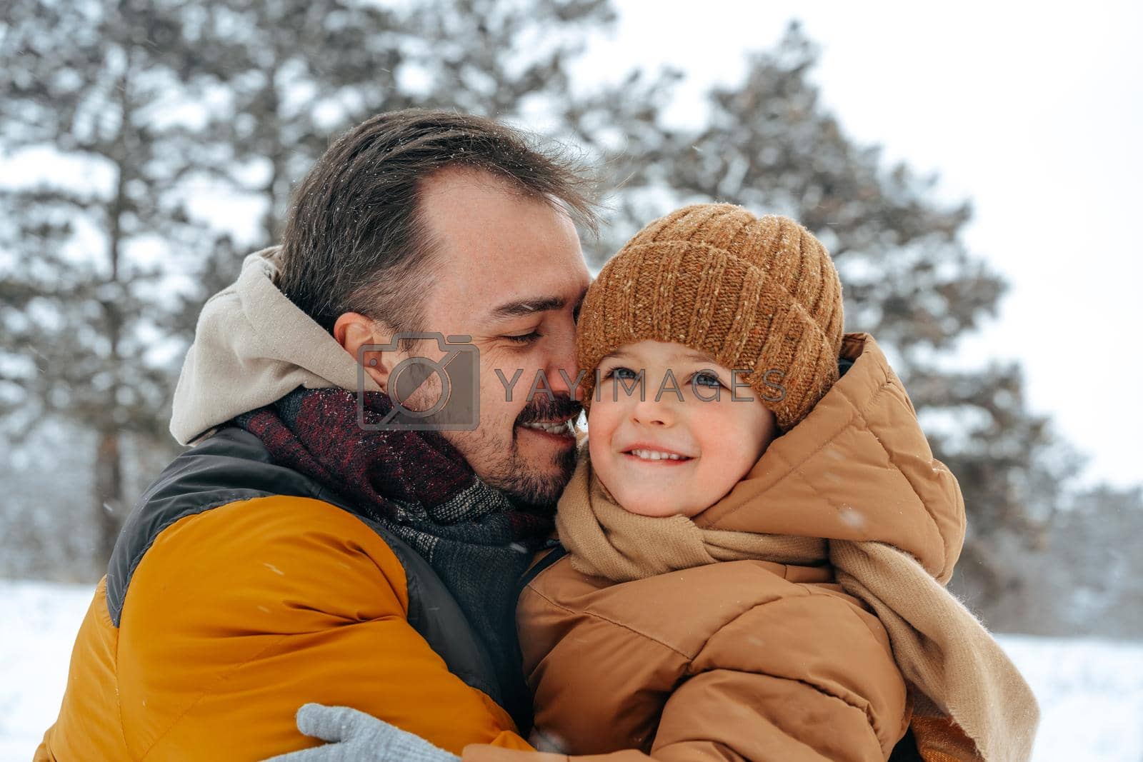 Father and son playing in the park on winter snowy day
