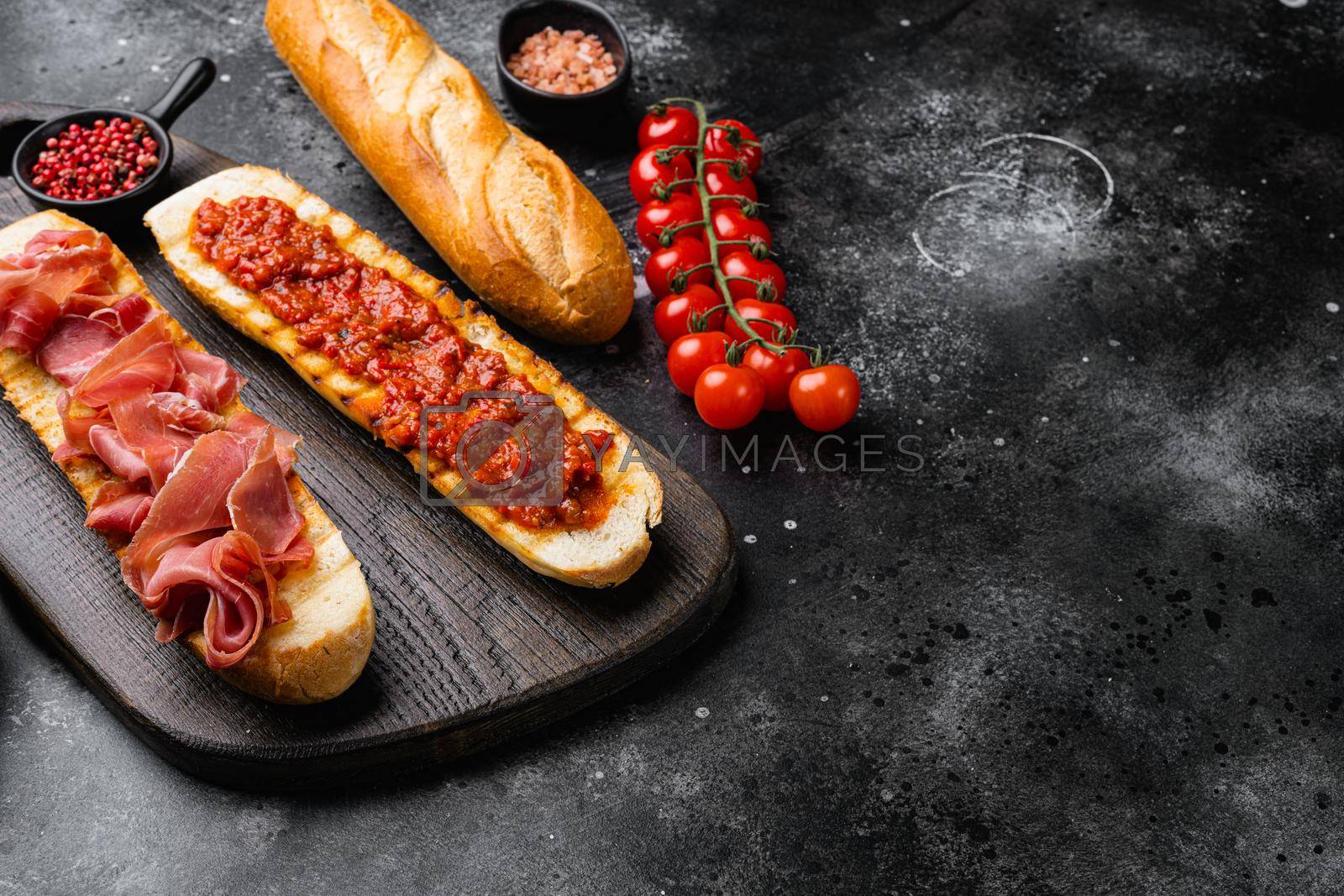 Royalty free image of Toasted bread slice with fresh tomatoes and cured ham, on black dark stone table background, with copy space for text by Ilianesolenyi