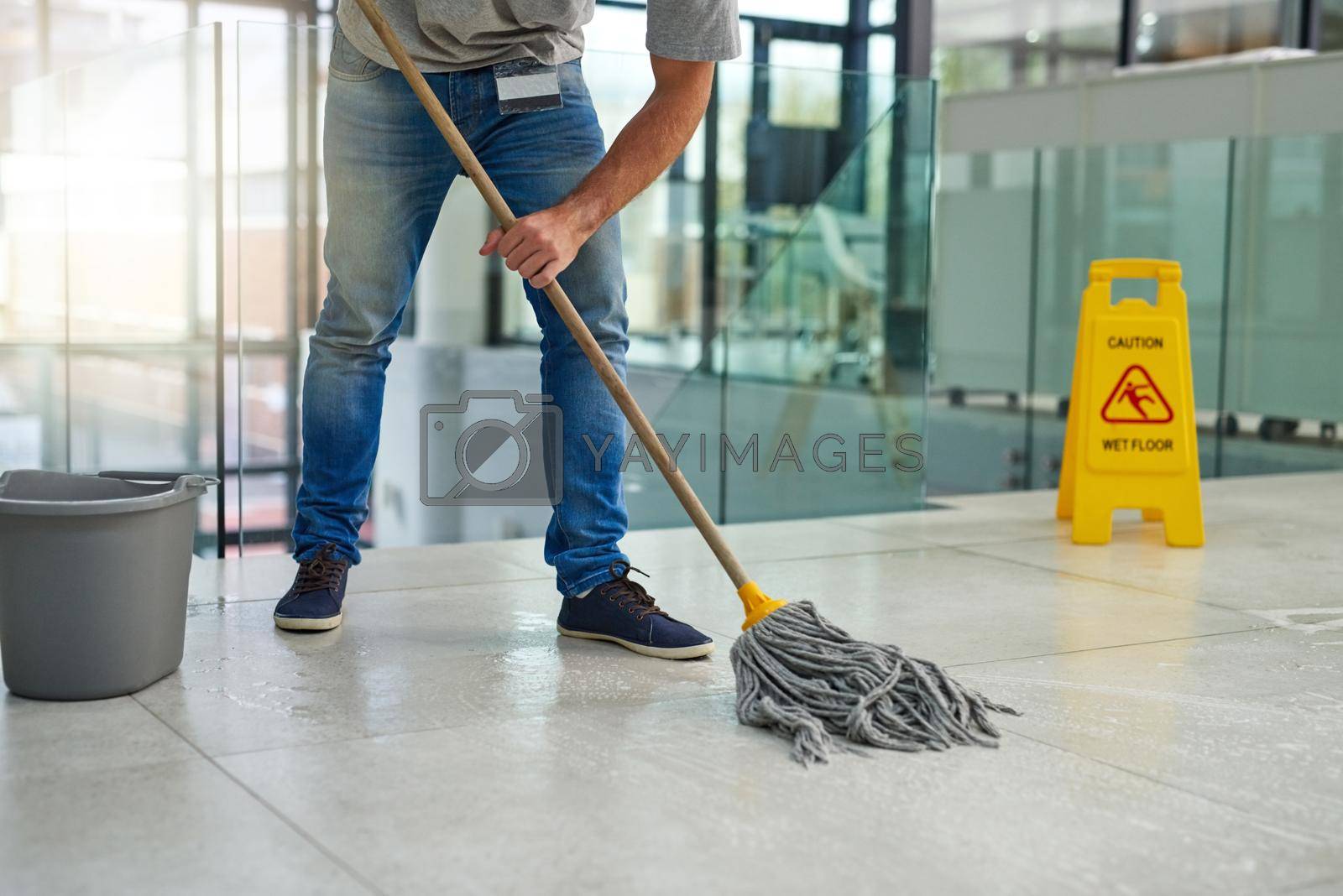 Royalty free image of Hell leave that floor spotless. Shot of an unrecognizable man mopping the office floor. by YuriArcurs