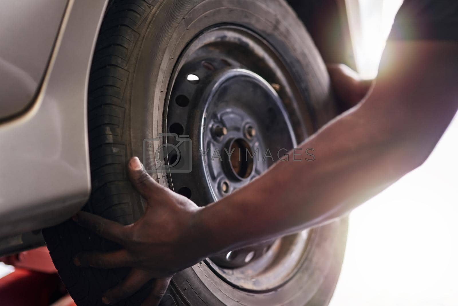 Royalty free image of Working with skill and precision. Cropped shot of a mechanic repairing a car tyre. by YuriArcurs