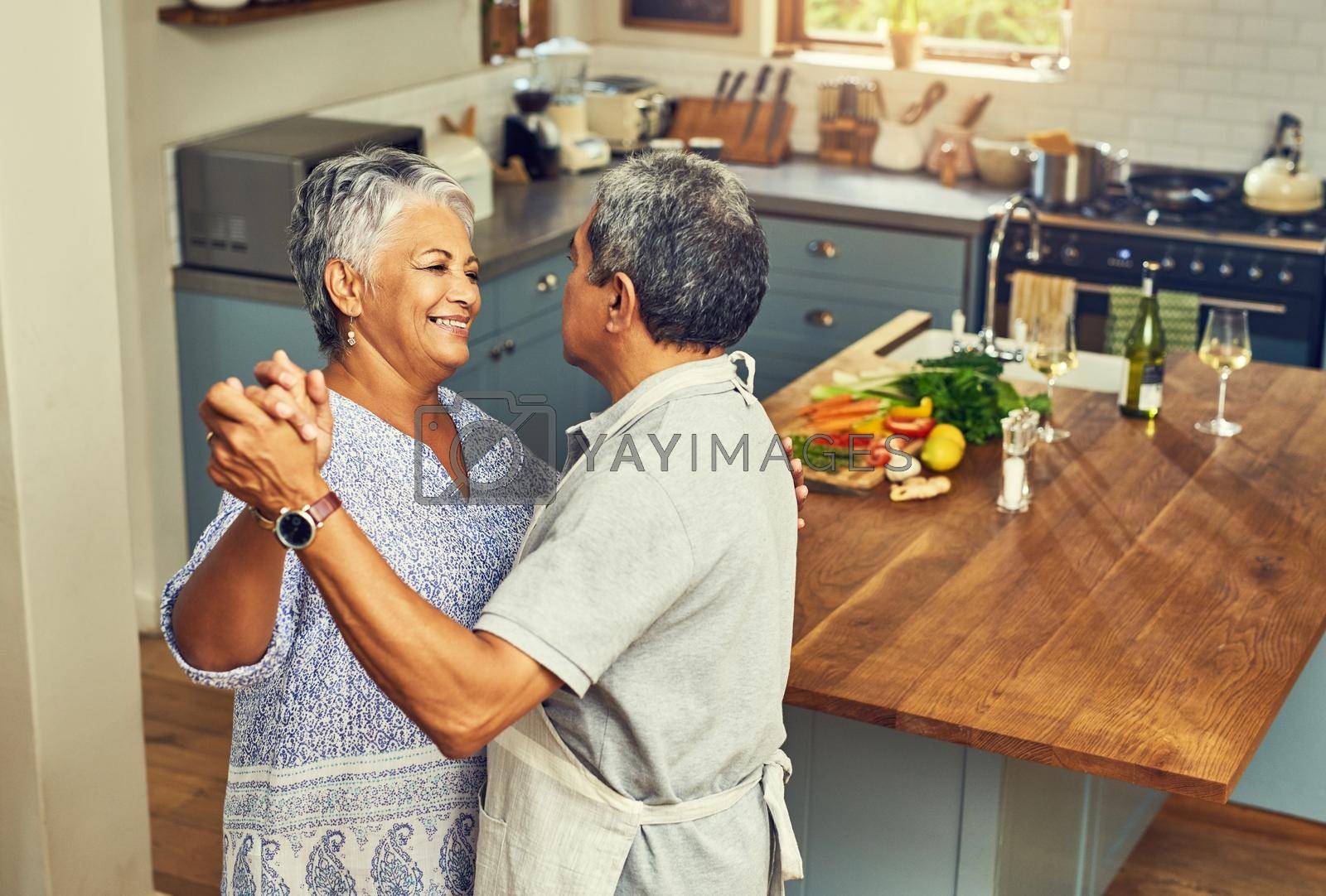 Shot of a happy mature couple dancing together while cooking in the kitchen at home.