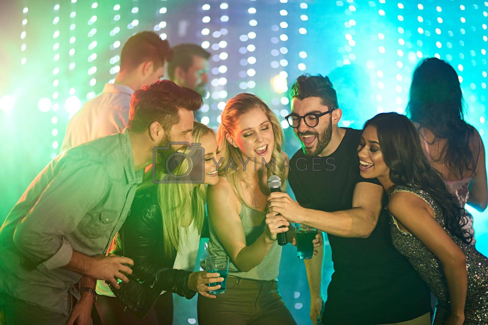 Shot of a group of friends singing karaoke at a party.