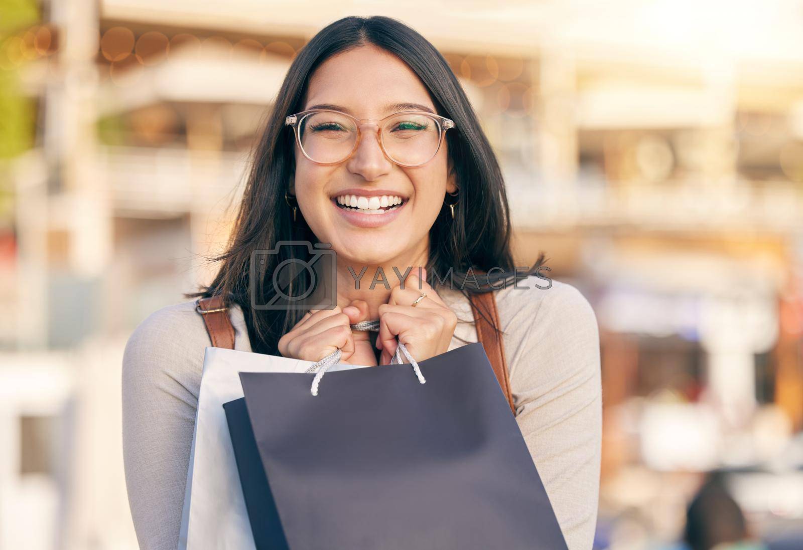 Royalty free image of I love the smell of money well spent. Portrait of an attractive young woman walking alone outside while shopping in the city. by YuriArcurs