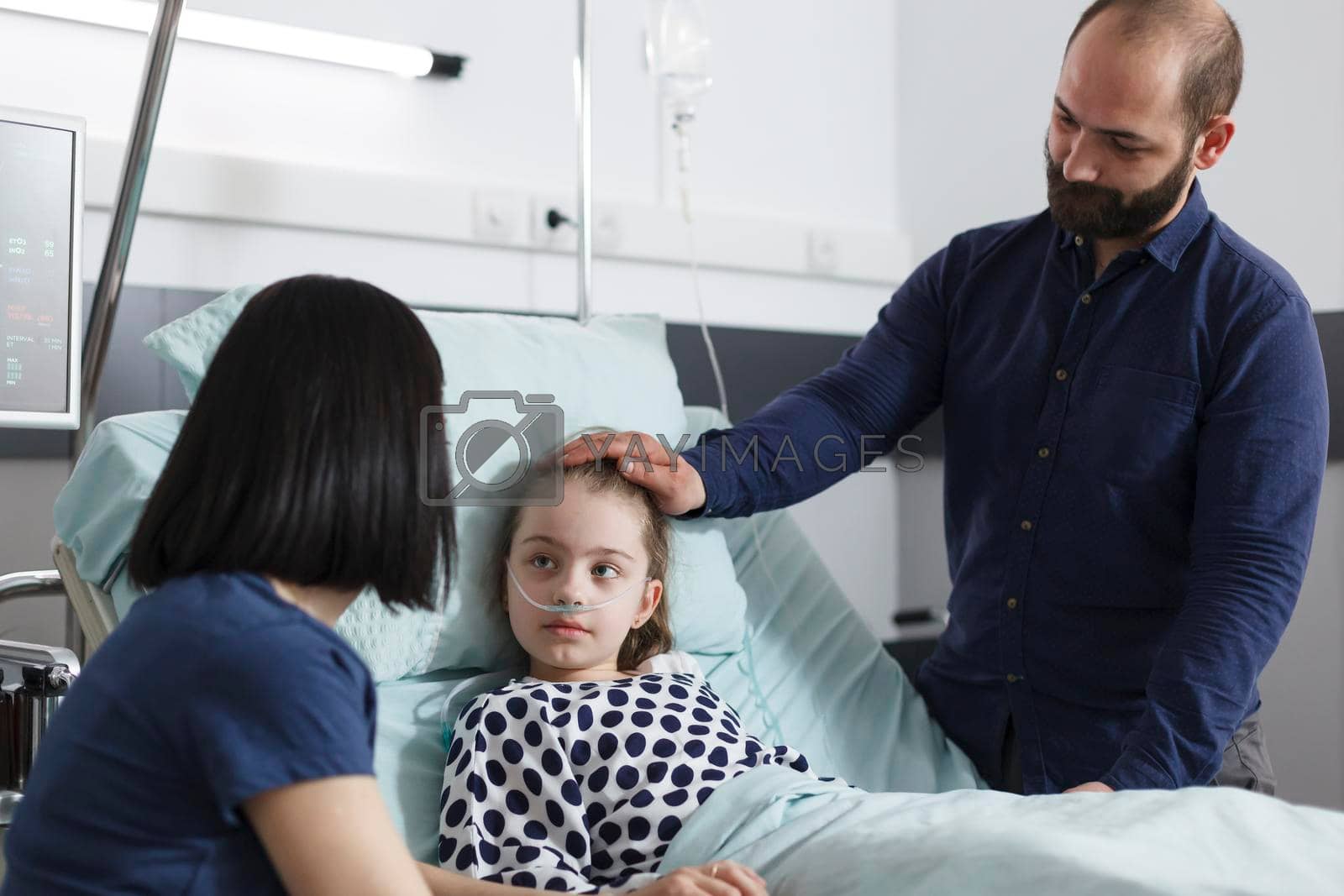 Careful parents talking with sick daughter about recovery period. Young mother and father discussing with ill child patient about consultation results and disease treatment while in recovery ward.