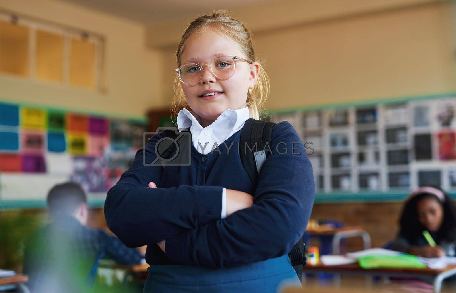 Shot of a young girl standing in her classroom at school with her arms folded.
