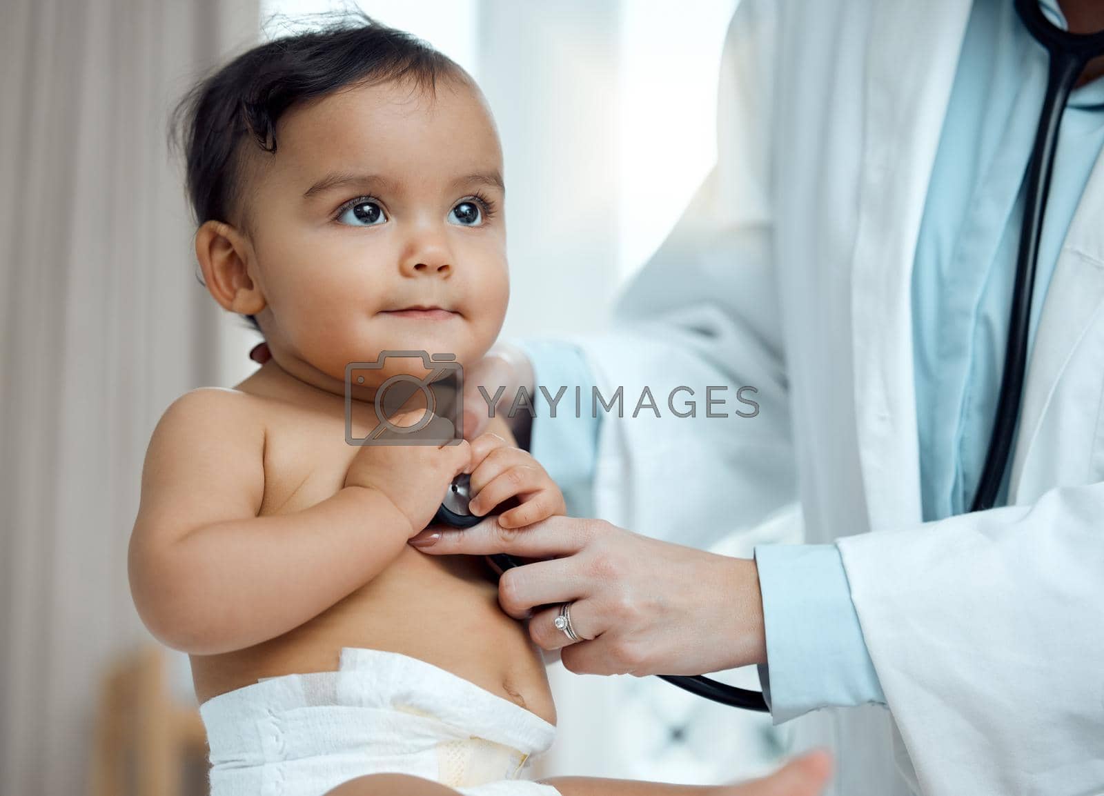 Royalty free image of What is it that youre hearing, doc. Closeup shot of a paediatrician using a stethoscope during a babys checkup in a clinic. by YuriArcurs