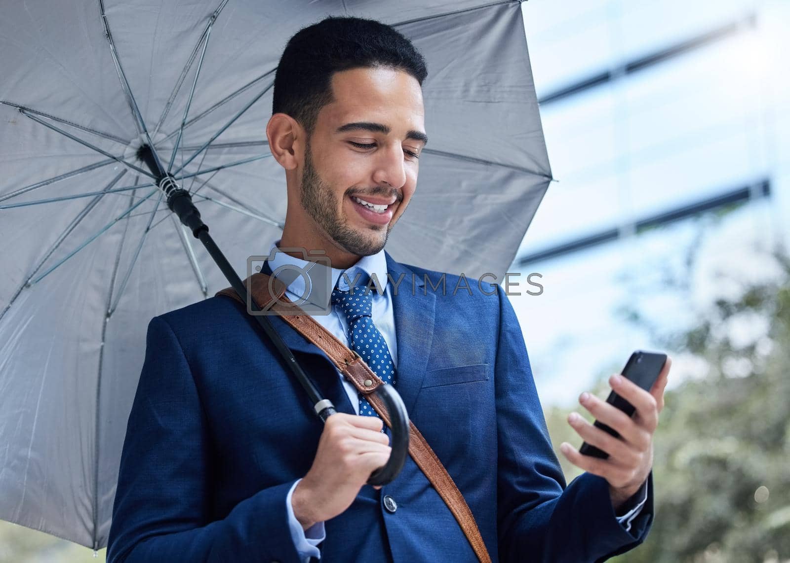 Royalty free image of Just the call Ive been waiting for. Cropped portrait of a handsome young businessman with an umbrella on his morning commute into work. by YuriArcurs
