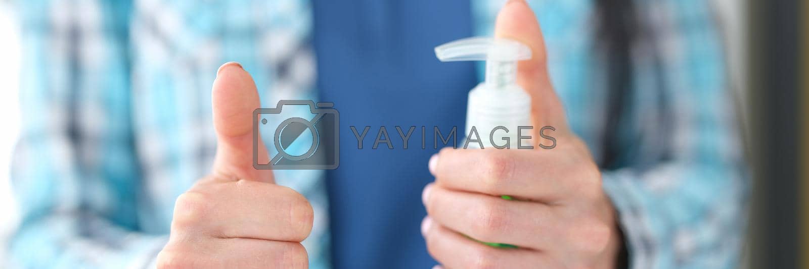 Royalty free image of Woman holding disinfectant gesture thumbs up closeup by kuprevich