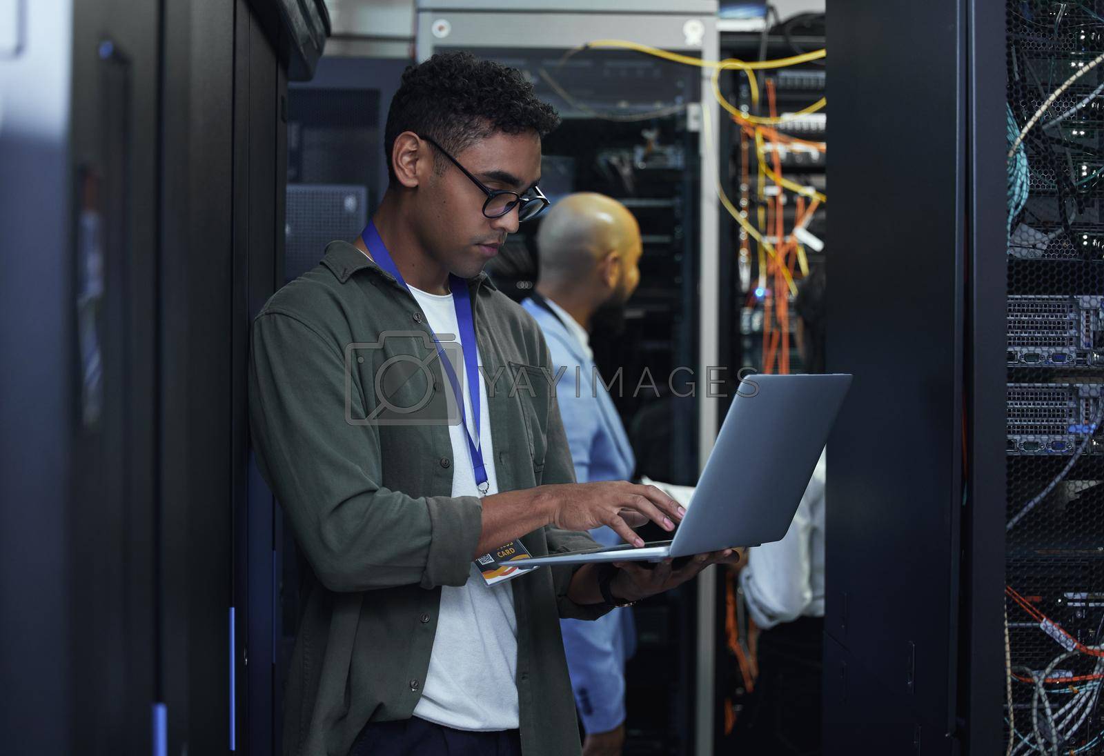 Royalty free image of IT work in progress. Cropped shot of two male IT support agents working together in a dark network server room. by YuriArcurs